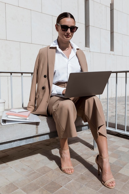 Foto donna piena del colpo che lavora al computer portatile