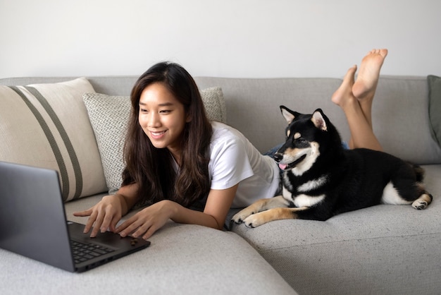 写真 ソファで犬と一緒に働くフルショットの女性