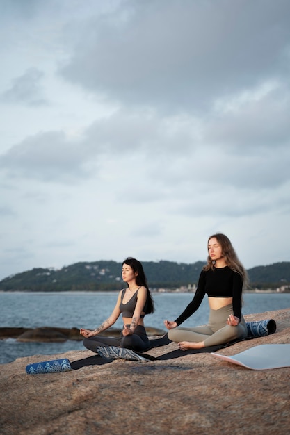 Donne a tutto campo che meditano in riva al mare