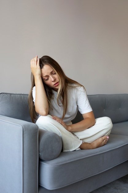 Photo full shot worried woman sitting on couch