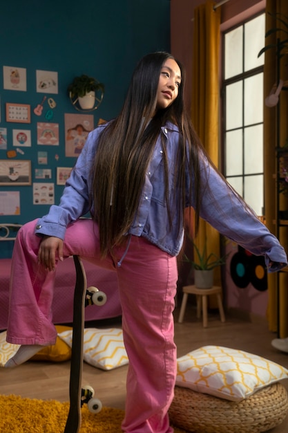 写真 屋内でスケートボードを持つフルショットの若い女の子