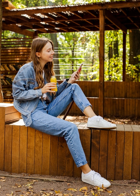 Photo full shot young woman holding fresh juice bottle