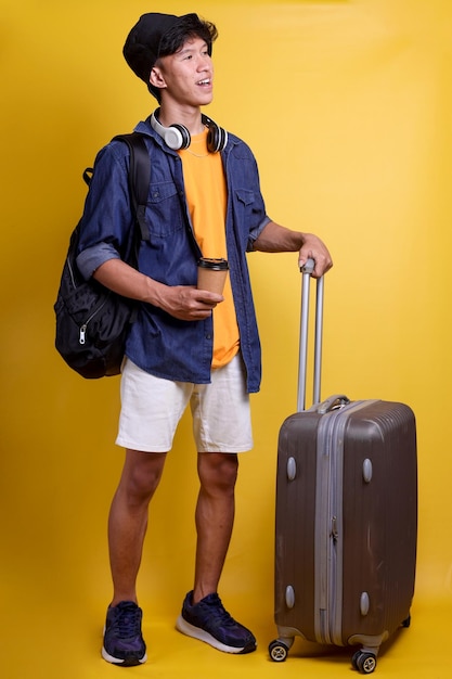 Full size body length side view of traveler young man with headphones on his neck wear casual cloth