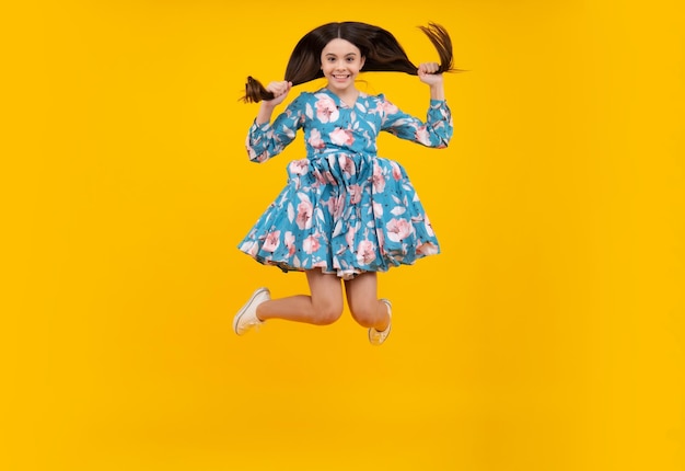 Full size length of young brunette girl teen student jump run go move hurry up isolated on yellow background studio