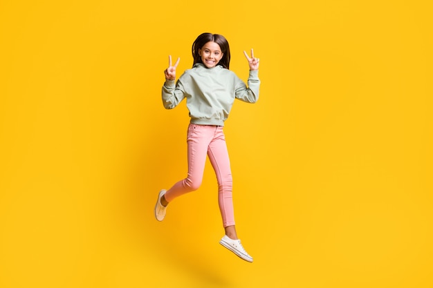 Full size photo of beautiful brunette hair satisfied kid jump show v-sign isolated on vivid yellow color background