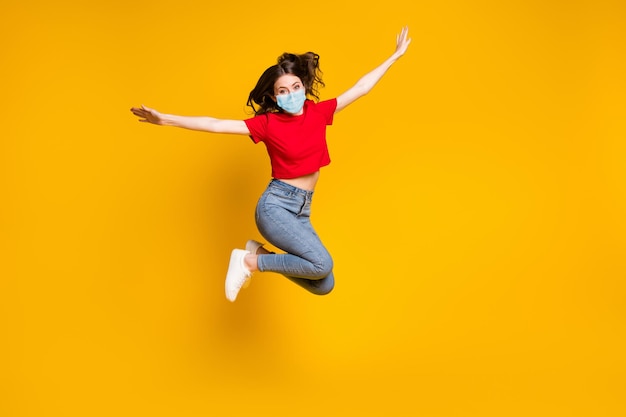 Foto a grandezza naturale di una ragazza pazza e allegra che salta e tiene la maschera indossata per mano isolata su uno sfondo di colore vivido