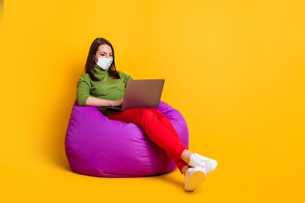 Full size photo of lady freelancer sit comfort violet bean bag working notebook wear mask isolated yellow color background