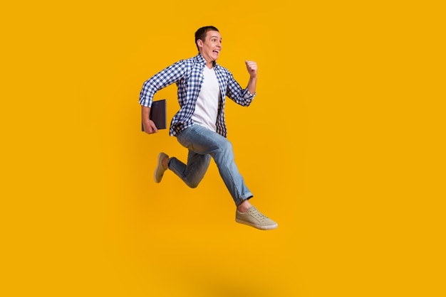 Full size photo of man jump runner sales discounts wear modern\
trendy outfit isolated over yellow color background