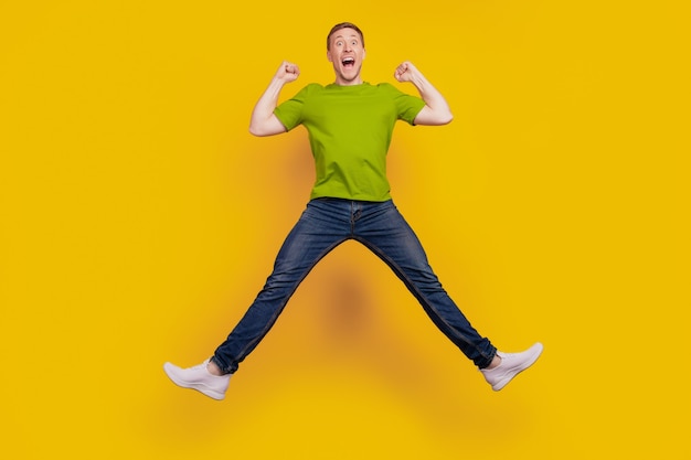 Full size photo of nice attractive cheerful optimistic guy having fun jump up ecstatic winner isolated over yellow background