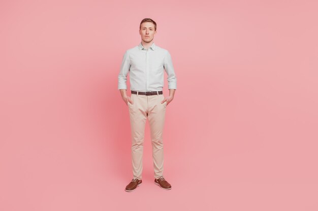 Full size photo of serious young man hold hands pockets confident formalwear isolated on pink color background