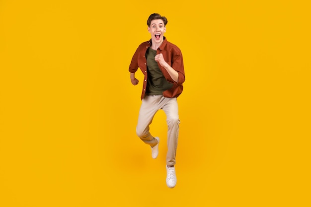 Full size photo of young crazy man amazed shock jump run hurry isolated over yellow color background