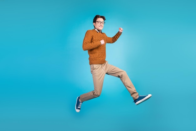 Full size photo of young excited man good mood jump up active walk run isolated over blue color background