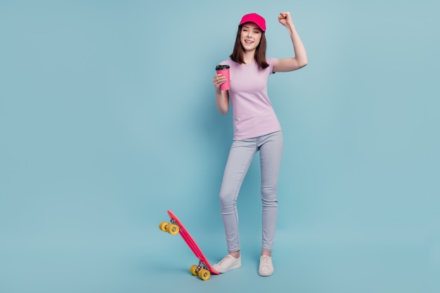 若い女の子のフルサイズの写真は勝利の成功を喜ぶコーヒーロングボードに乗る孤立したターコイズ色の背景を飲む