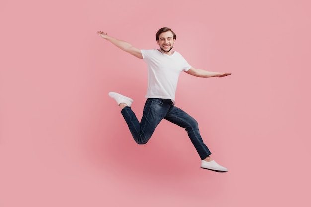 Full size photo of young happy excited smiling positive man jumping hands wings fly isolated on pink color background