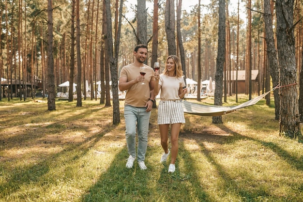 Ritratto a grandezza naturale di un bel ragazzo sorridente e della sua bella ragazza contenta che alzano gli occhiali per la loro felicità