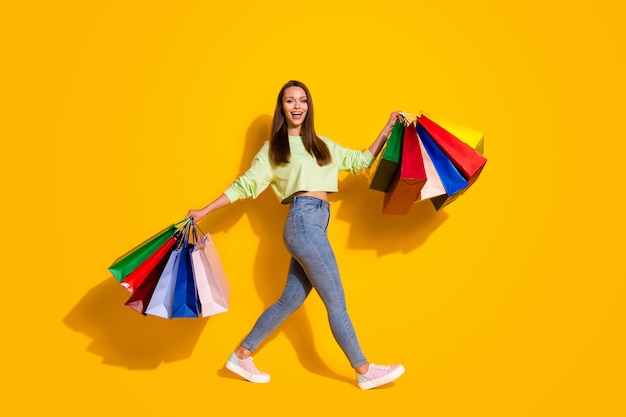 Foto del profilo a grandezza naturale di una bella donna maniaca dello shopping che cammina nel centro commerciale porta borse