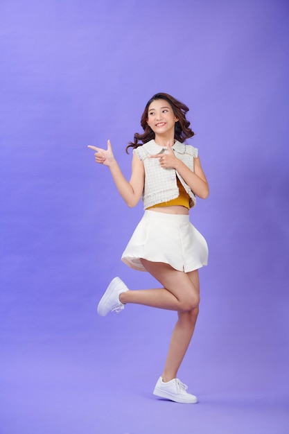 Full size young woman jump pointing back behind on workspace area copy space isolated on purple color background
