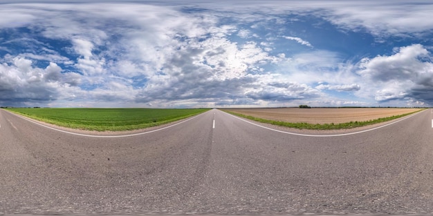 Full spherical seamless panorama 360 degrees angle view on no traffic asphalt road among fields with cloudy sky in equirectangular projection VR AR content