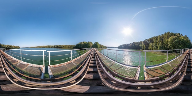 등방형 등거리 투영 VR AR 콘텐츠에서 호수 360도 파노라마를 가로지르는 거대한 기차 철도 교량의 강철 프레임 건설에 대한 완전한 구형 이음매 없는 파노라마 360도 각도 보기