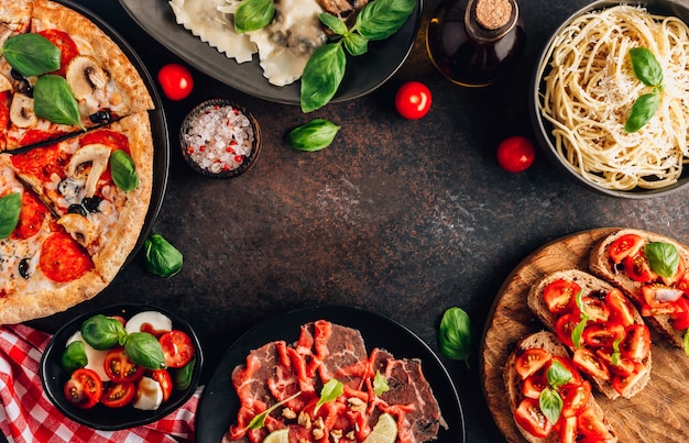 Photo full table of italian meals on plates on black background