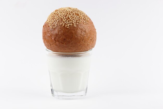 흰색 배경에 격리된 참깨가 있는 호밀빵이 있는 흰색 우유의 완전 투명한 유리 유용한 아침 식사 근접 촬영 건강 식품 개념
