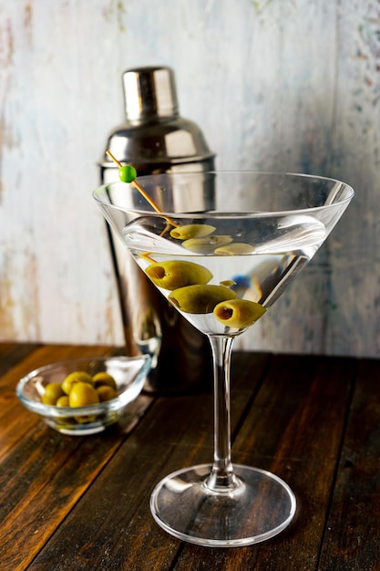 Un'inquadratura verticale completa di un bicchiere da martini con olive su sfondo chiaro. Foto Premium