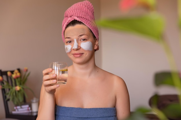 Full view of happy woman with mask on face at home with glass water