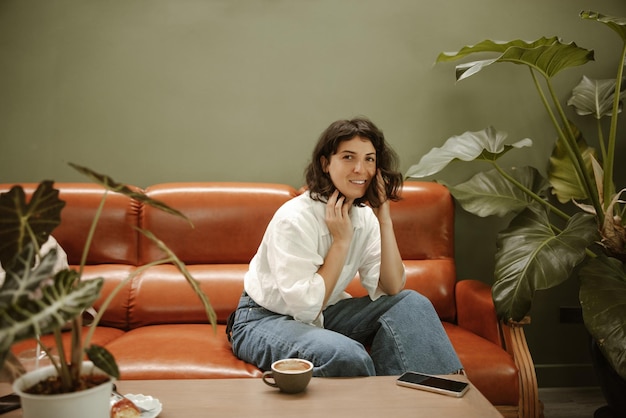 Full view of smiling woman look at camera in cafe