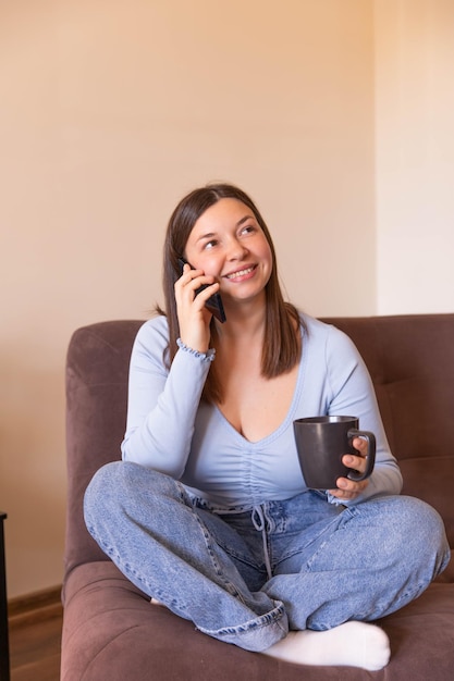 Full view of smiling woman sitting talk on phone