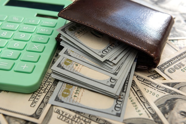 Фото Полный кошелек банкноты 100 долларов с калькулятором в качестве бизнес-фона, концепция экономии