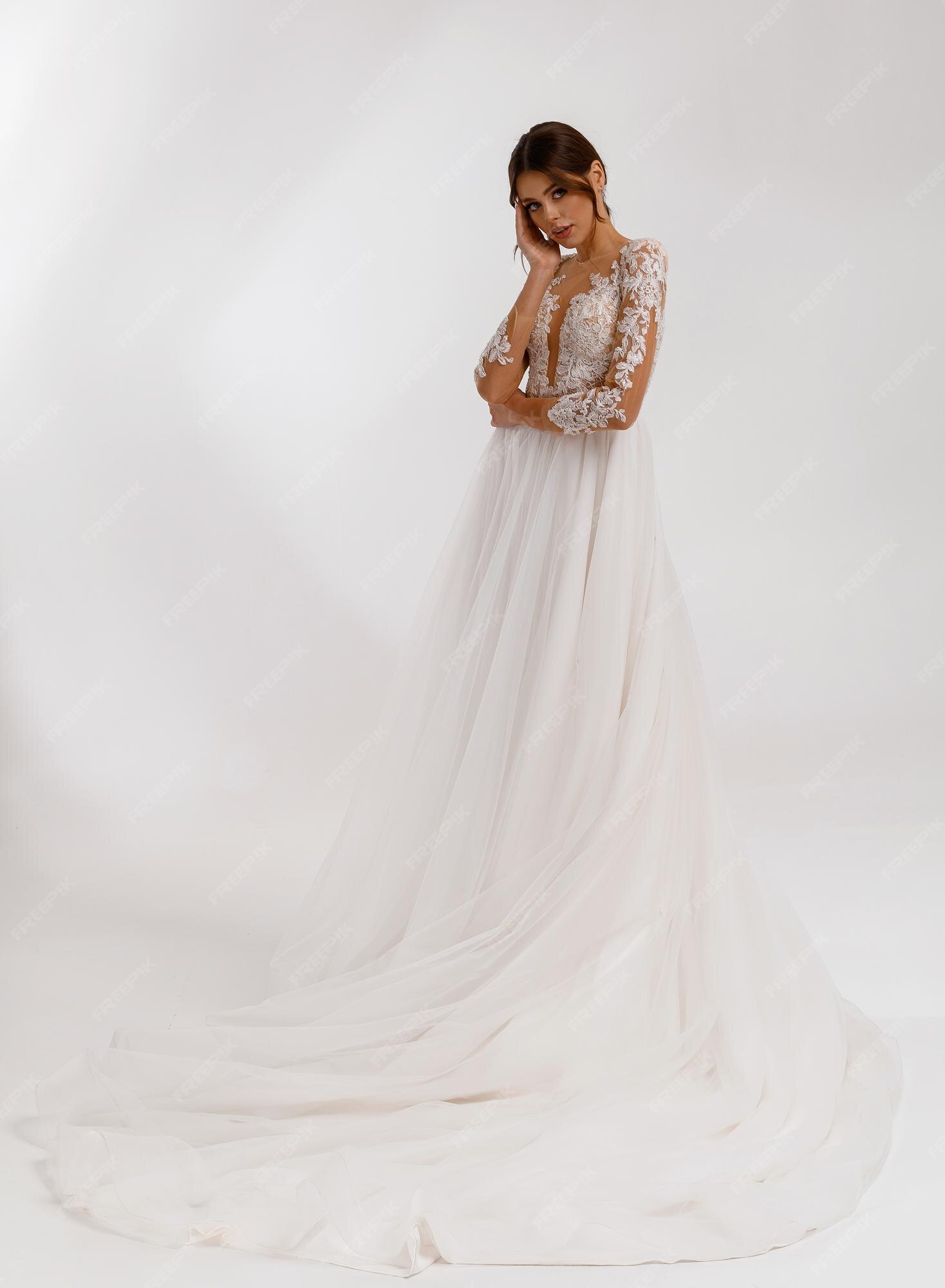 Premium Photo | Fulllength portrait of beauty young bride girl in long stylish dress wedding dress with lace beads and long sleeves adorable woman model having wedding hairstyle posing alone at the Premium Photo | Fulllength portrait of beauty young bride girl in long stylish dress wedding dress with lace beads and long sleeves adorable woman model having wedding hairstyle posing alone at the