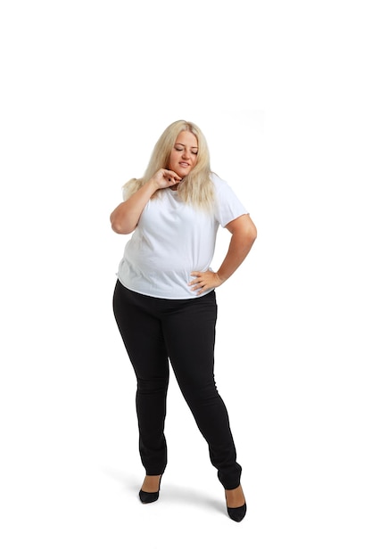 Fulllength portrait of plussize woman wearing white tshirt and jeans posing isolated on white studio