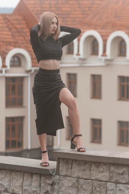 Fulllength portrait of slender young girl in long tightfitting skirt and crop top with slit and heels Vertical frame