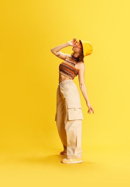 Fulllength portrait of stylish young girl in trendy cargo pants knitted top and panama standing