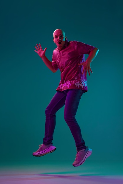 Photo fulllength portrait of young bald man with moustache in stylish clothes emotionally jumping against