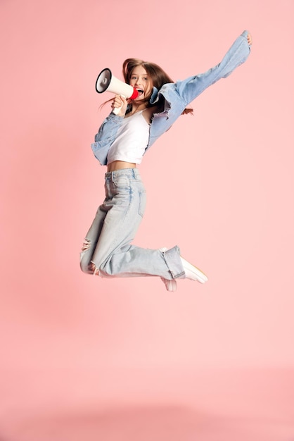 Fulllength portrait of young beautiful girl student in casual clothes jumping and shouting in