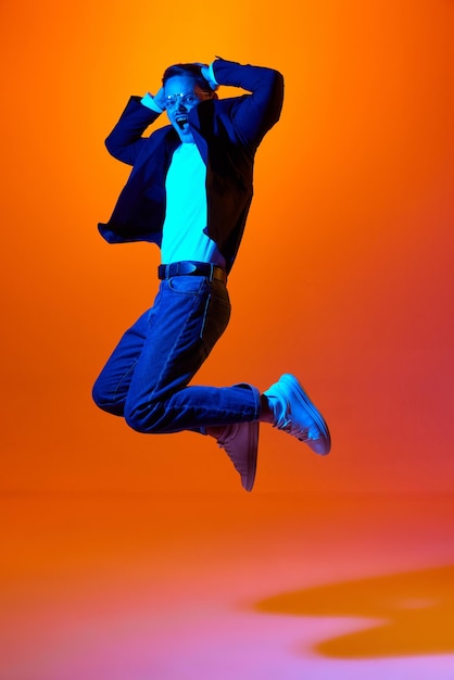 Fulllength portrait of young emotive man in stylish casual clothes emotinally jumping against