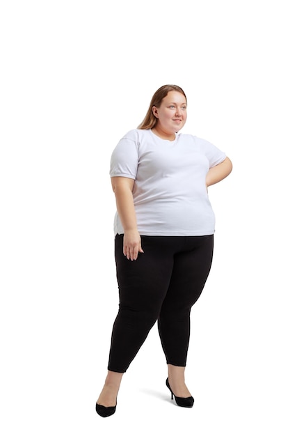 Fulllength portret van plussize vrouw, gekleed in witte t-shirt en jeans poseren geïsoleerd op witte studio