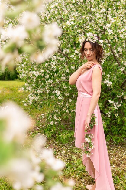 Foto una donna a figura intera in un vestito vicino a un albero di primavera in fiore romantico umore felice