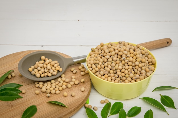 Fully Soy beans in the bowl and spoon on white table .