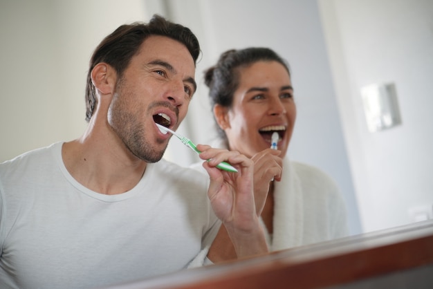  Fun attractive couple brushing teeth together                              