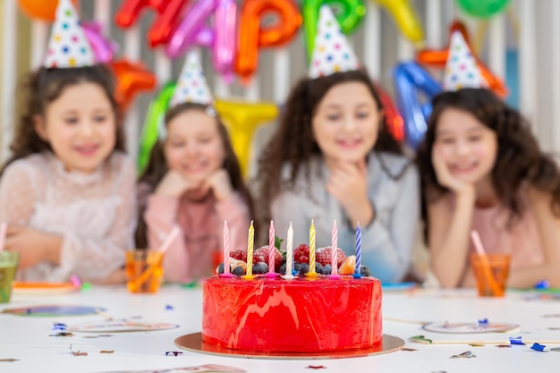 装飾された部屋での子供たちの楽しい誕生日パーティー 手前の誕生日ケーキ