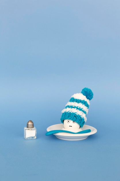 Photo fun breakfast concept with boiled eggs wearing knitted woolen hats on blue background