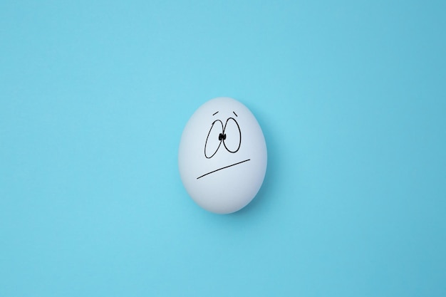 Fun face of white egg in against blue background Copy space Emoticons concept Art collage