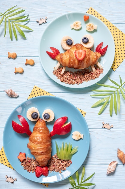 Cibo divertente per bambini. graziosi croissant di granchio e aragosta con frutta per la colazione dei bambini