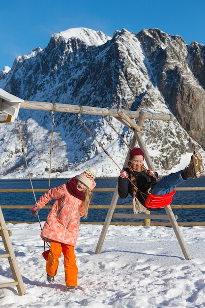 楽しい幸せな生活。ロフォーテン諸島でブランコに揺れる女の子の妹。ノルウェー