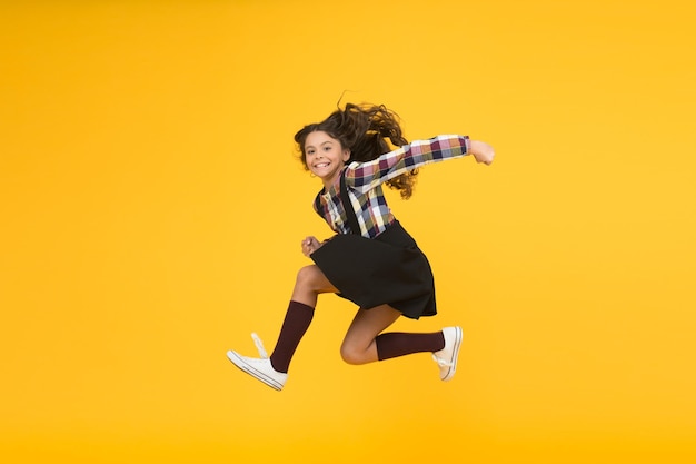 Fun and jump Happy childrens day Jump concept Break into Feel inner energy Girl with long hair jumping on yellow background Carefree kid summer holiday Time for fun Active girl feel freedom