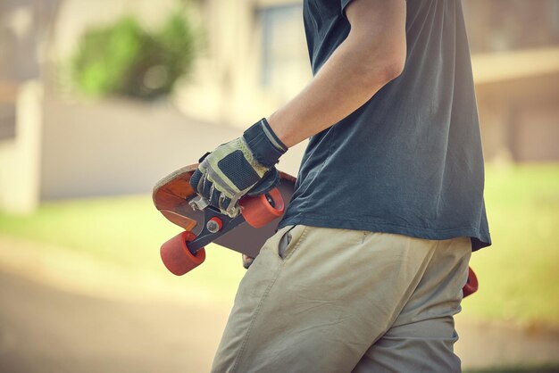 Fun skateboard and man skateboarding in a neighborhood for fitness exercise and training Sport cardio and hands of a teenager with a board in the street to travel commute and playing in the road