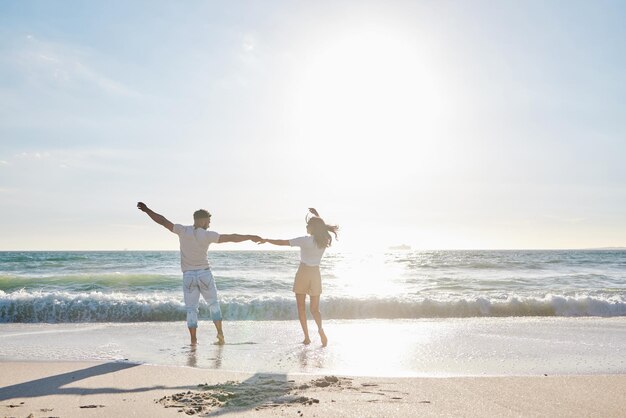 太陽の下で楽しい。ビーチで楽しんでいる愛情のこもった若いカップルのフルレングスのショット。