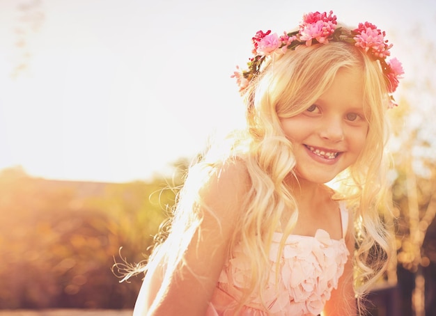 Photo fun in the sun shot of a happy little girl looking at the camera while standing in the sun outside in nature